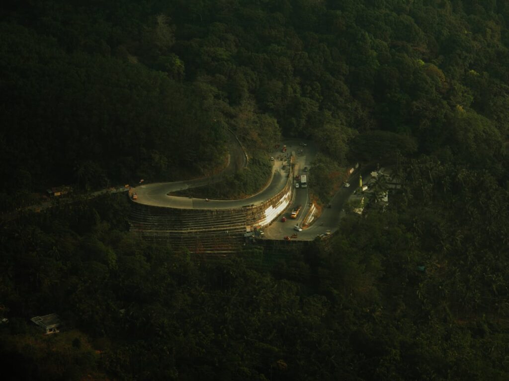 A scenic aerial view of a winding road through the dense forests of Wayanad, India.